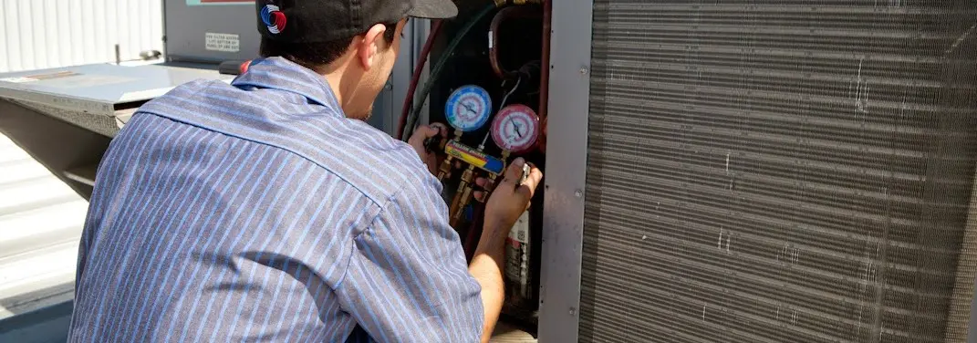 HVAC technician servicing a condenser unit in West Seneca